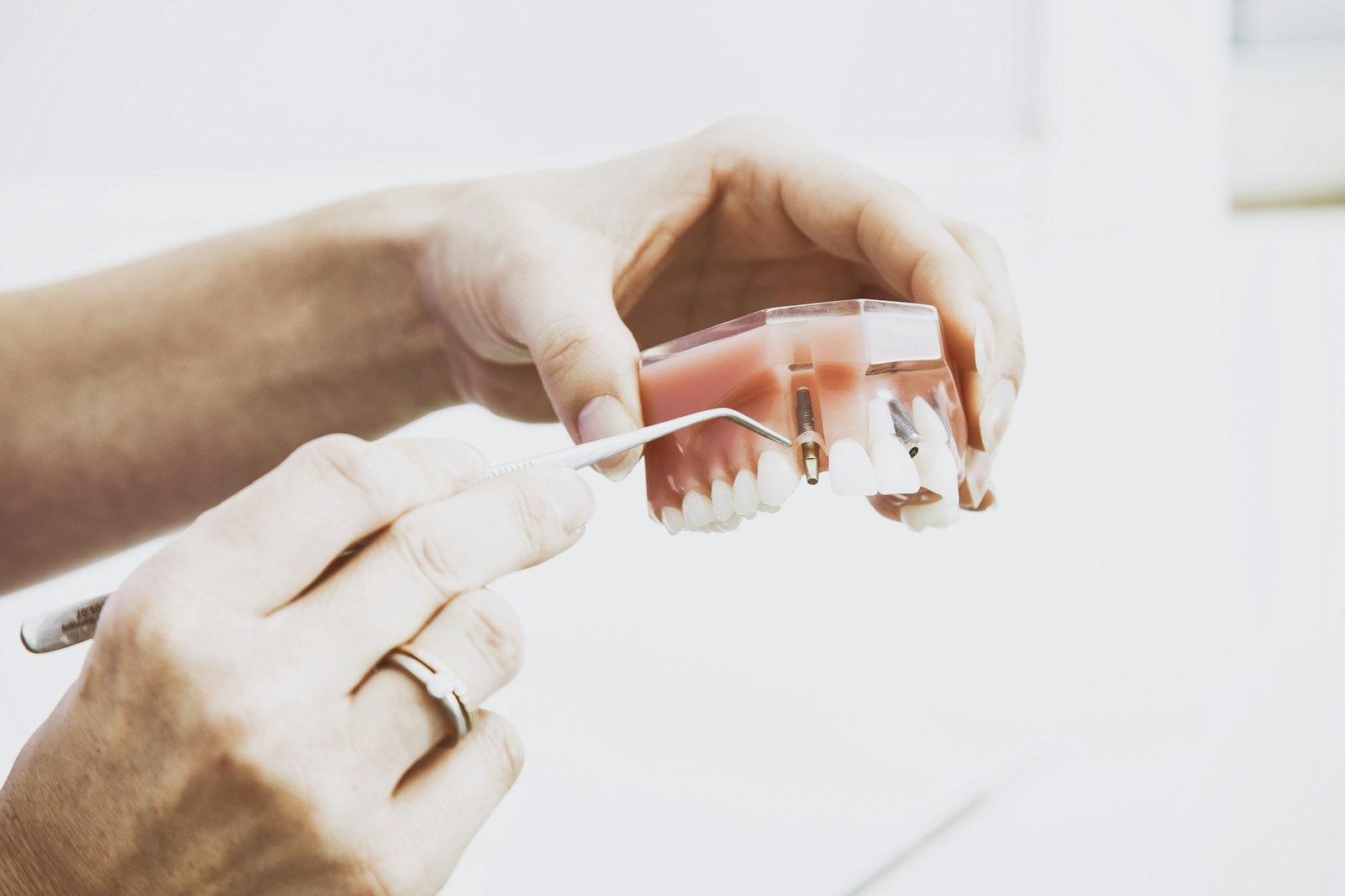 Person wearing silver-colored ring while holding denture