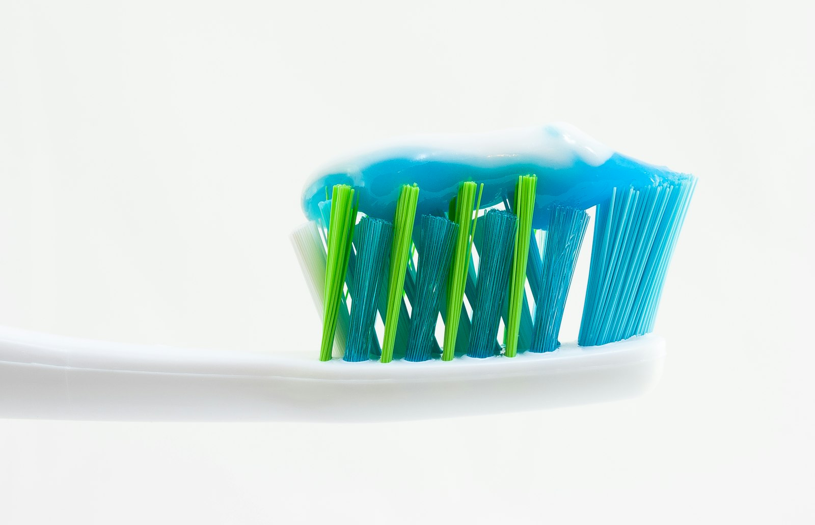 freestocks-Qx5QNarbrUM-unsplash White, blue, and green toothbrush with blue toothpaste